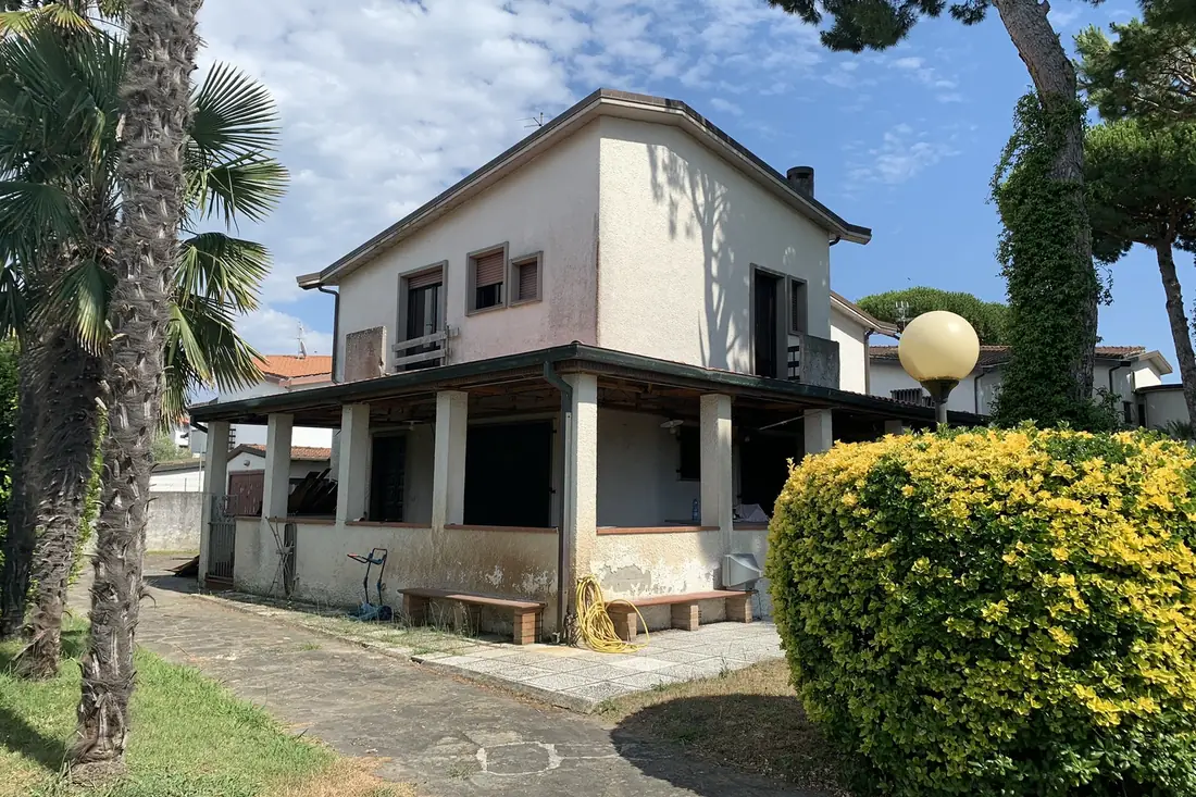 Villa a Pietrasanta prima della ristrutturazione: facciata scrostata e portico con la vecchia pergola in legno